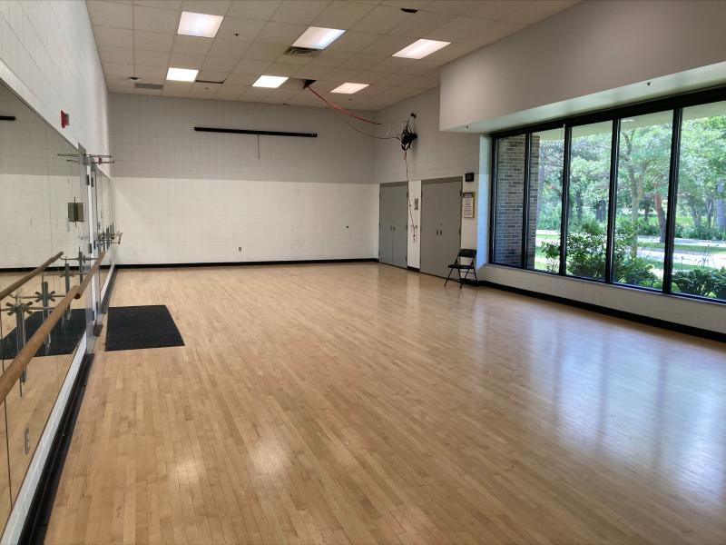 Empty multipurpose room at Bloomington Ice Garden with hardwood floors and large windows to the right