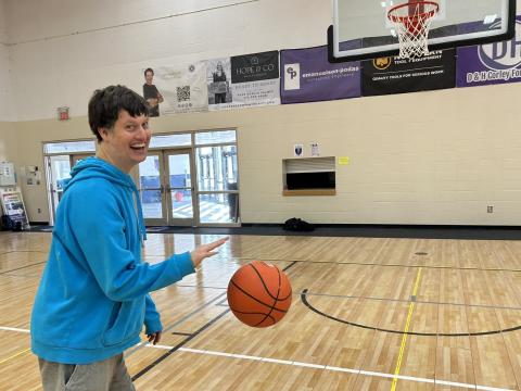 Smiling adult playing basketball in a brightly-lit gym