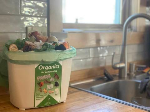 Organics recycling bin sitting on a kitchen counter next to a sink