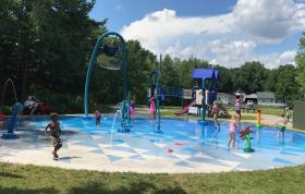 Young kids playing and having fun with sprayers and other water features at the Cedarcrest Park splash pad