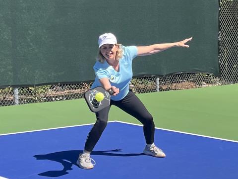 Photo of Rachael Kroog playing pickleball in athletic apparel on a blue court