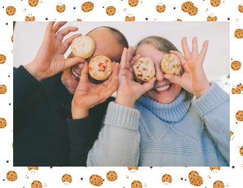 Two older adults laughing while holding cookies up to their eyes