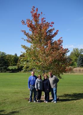 Family standing by a memorial tree planted at Dwan Golf Course