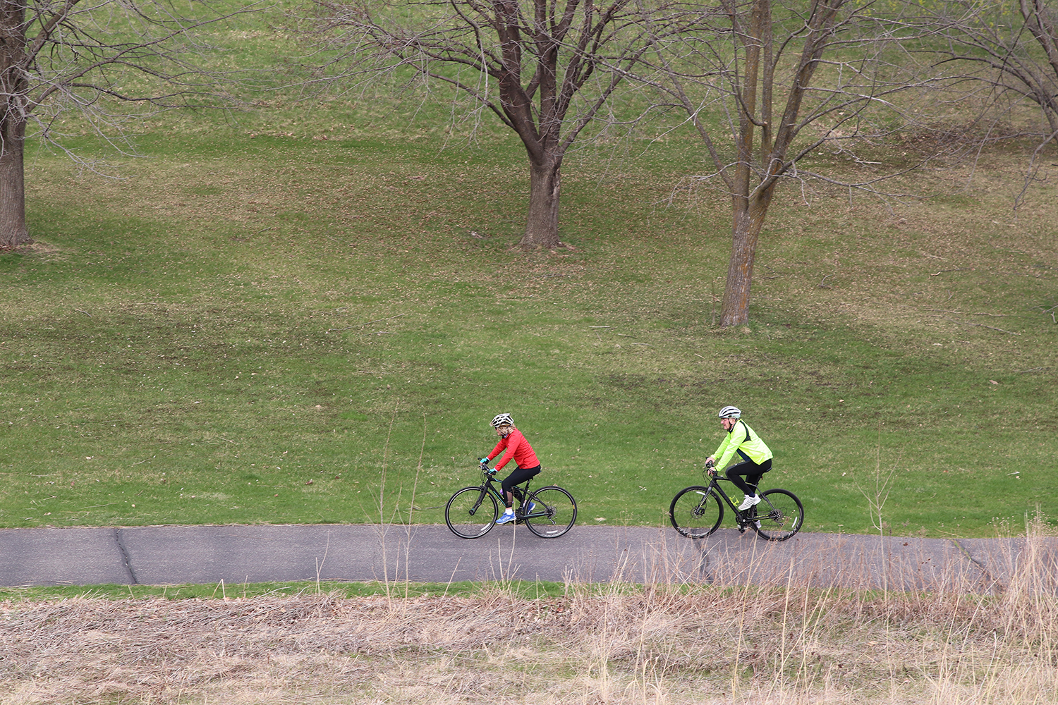 Two adults riding bikes along a paved path