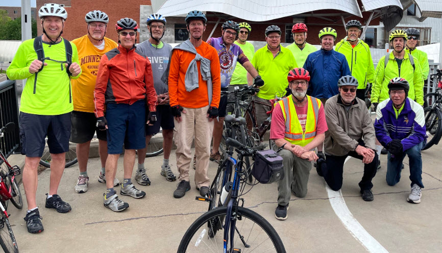 Group of adults ages 55+ with bicycles and helmets smiling for the camera