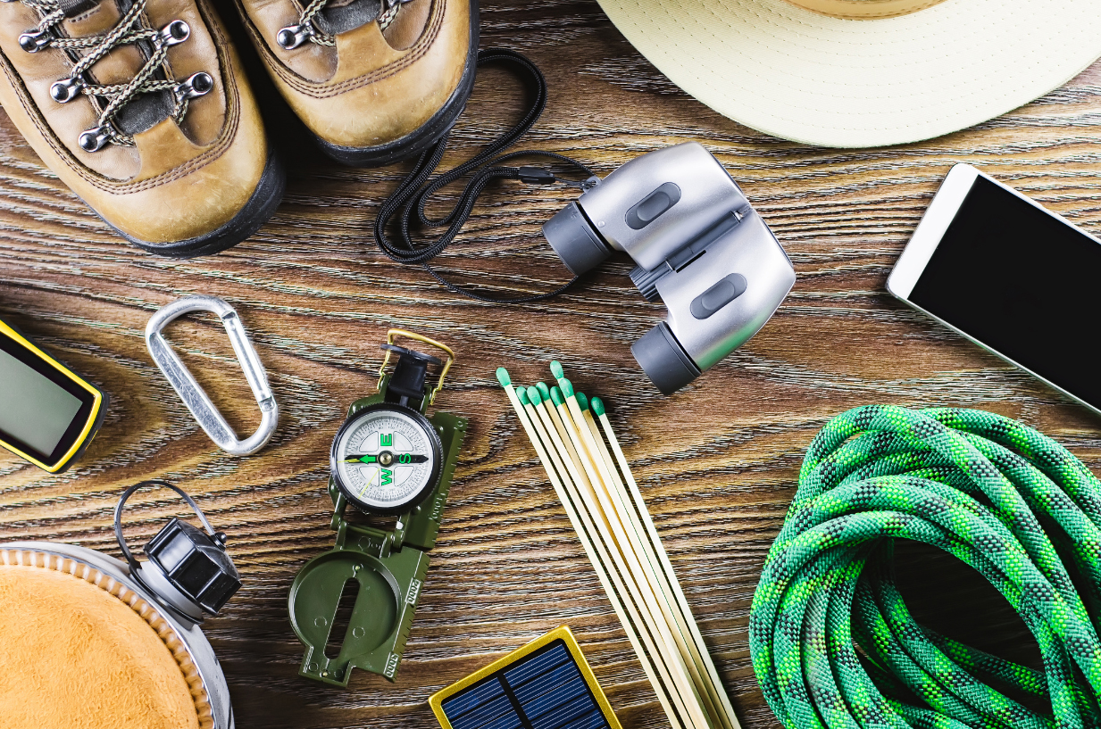Wilderness survival tools montage with boots, compass, rope, canteen, carabiner, binoculars, matches, gps device and more