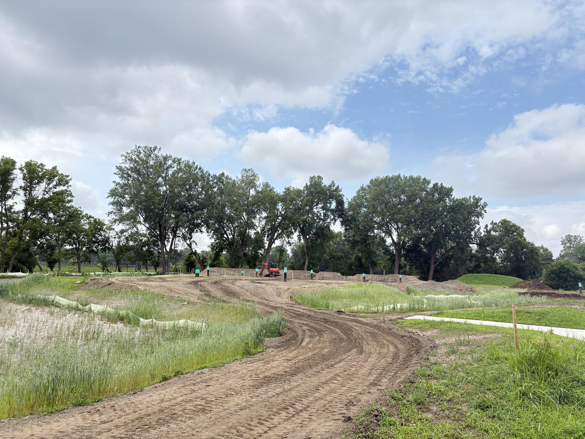 Dirt path at Tretbaugh bike skills park with workers in background