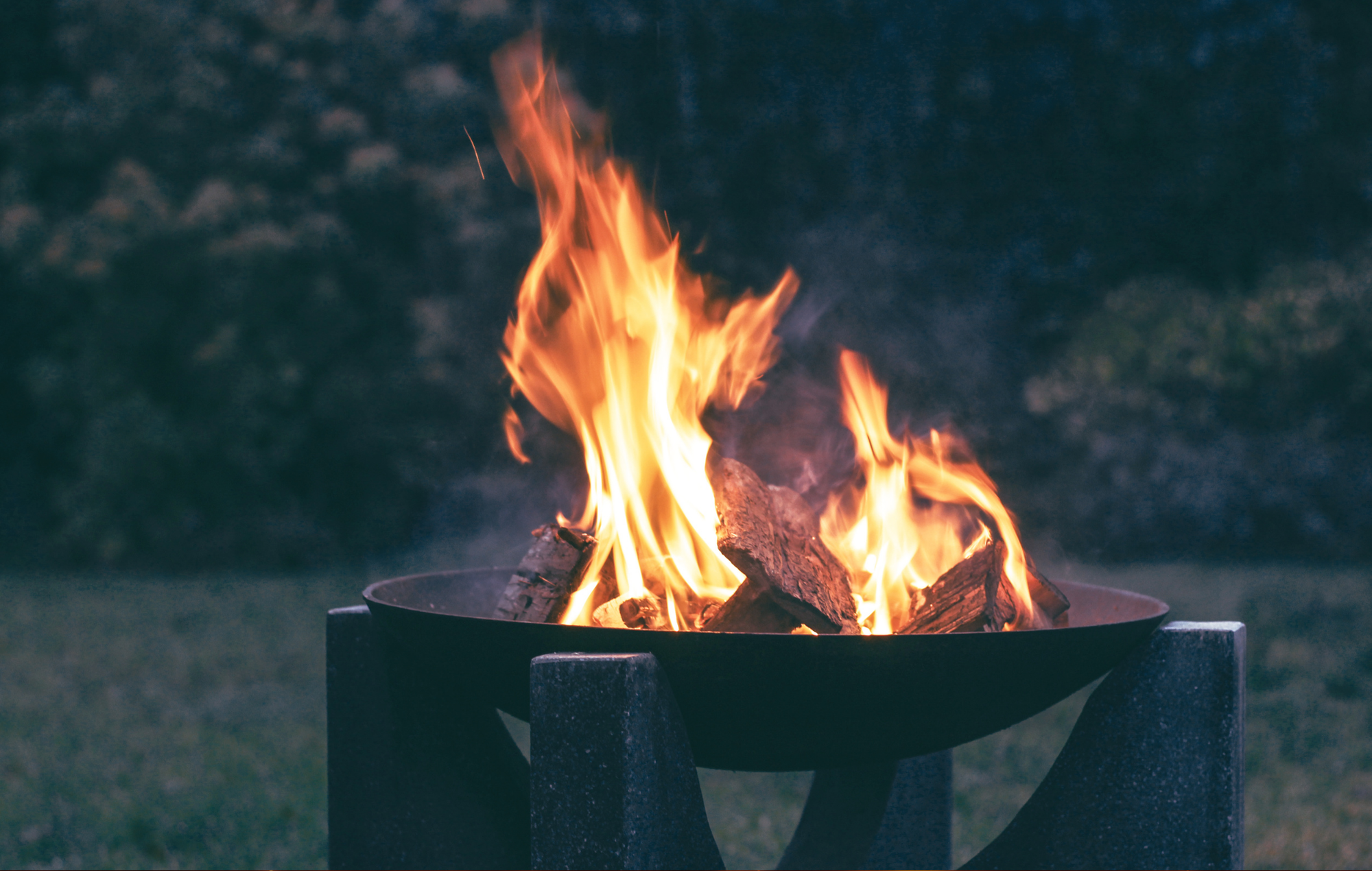 outdoor fire pit with a roaring wood fire at dusk