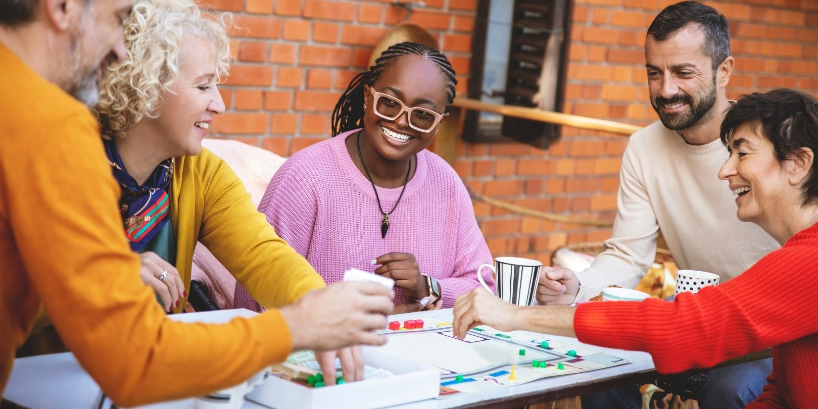 five adults playing a board game similar to monopoly