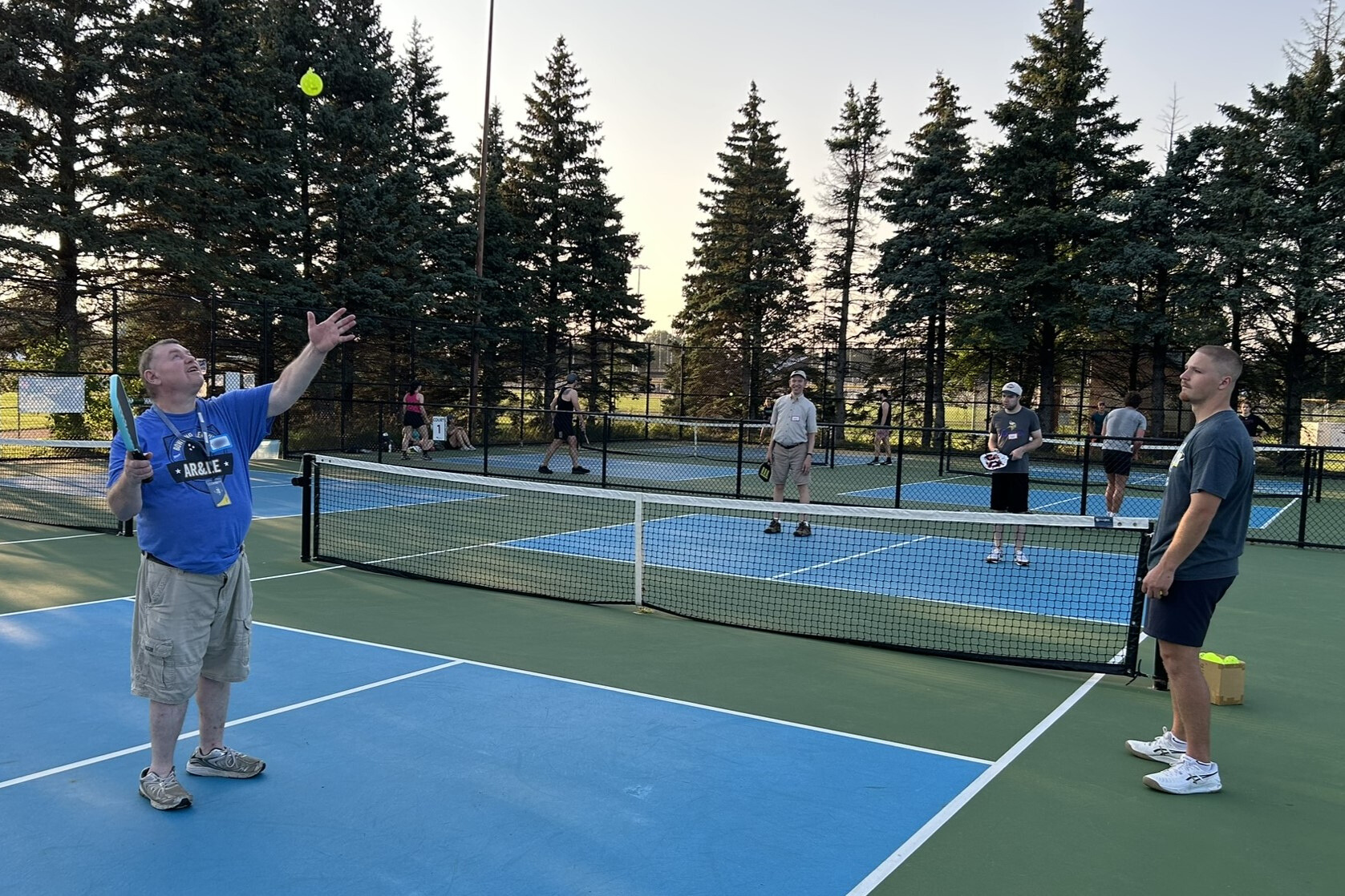 Adults with disabilities playing pickleball outdoors on a blue court