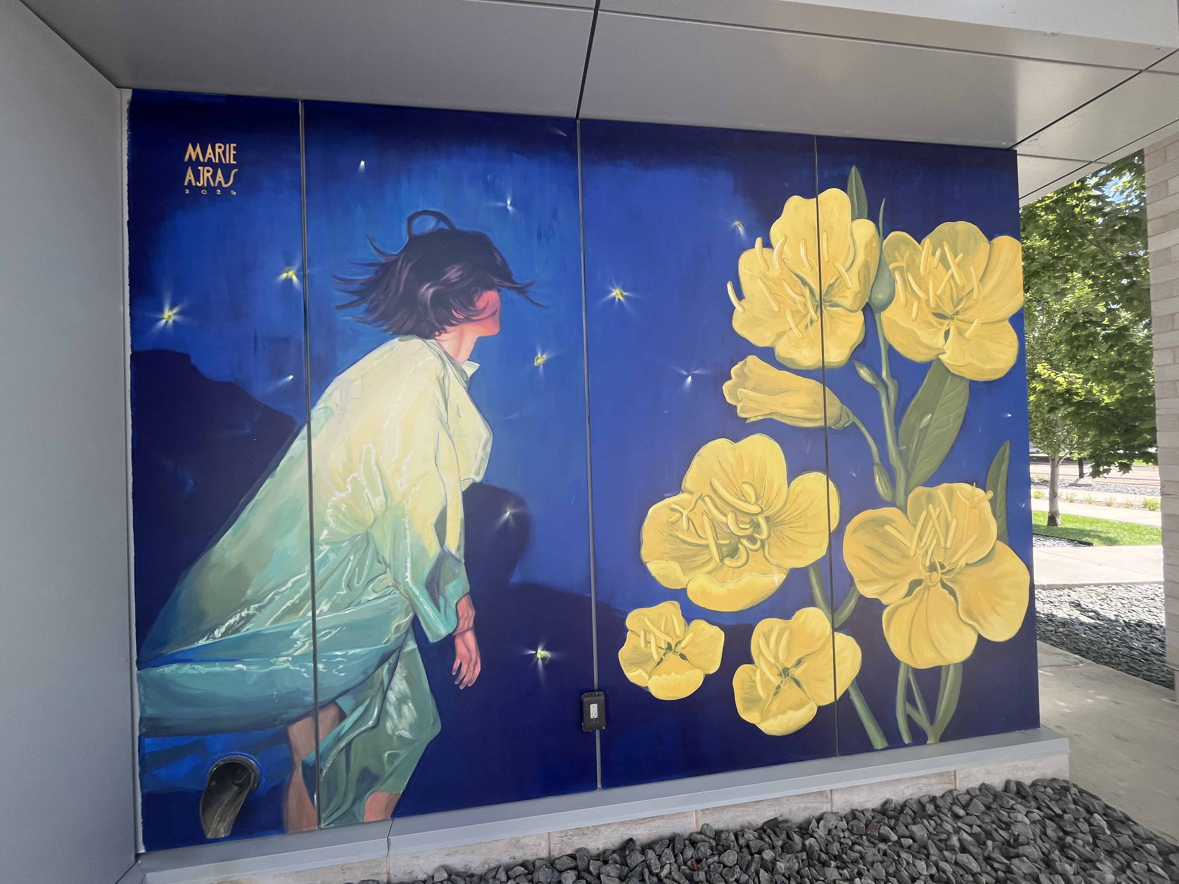 Mural on sectioned wall with blue background, figure with flowing garment, and large yellow flowers