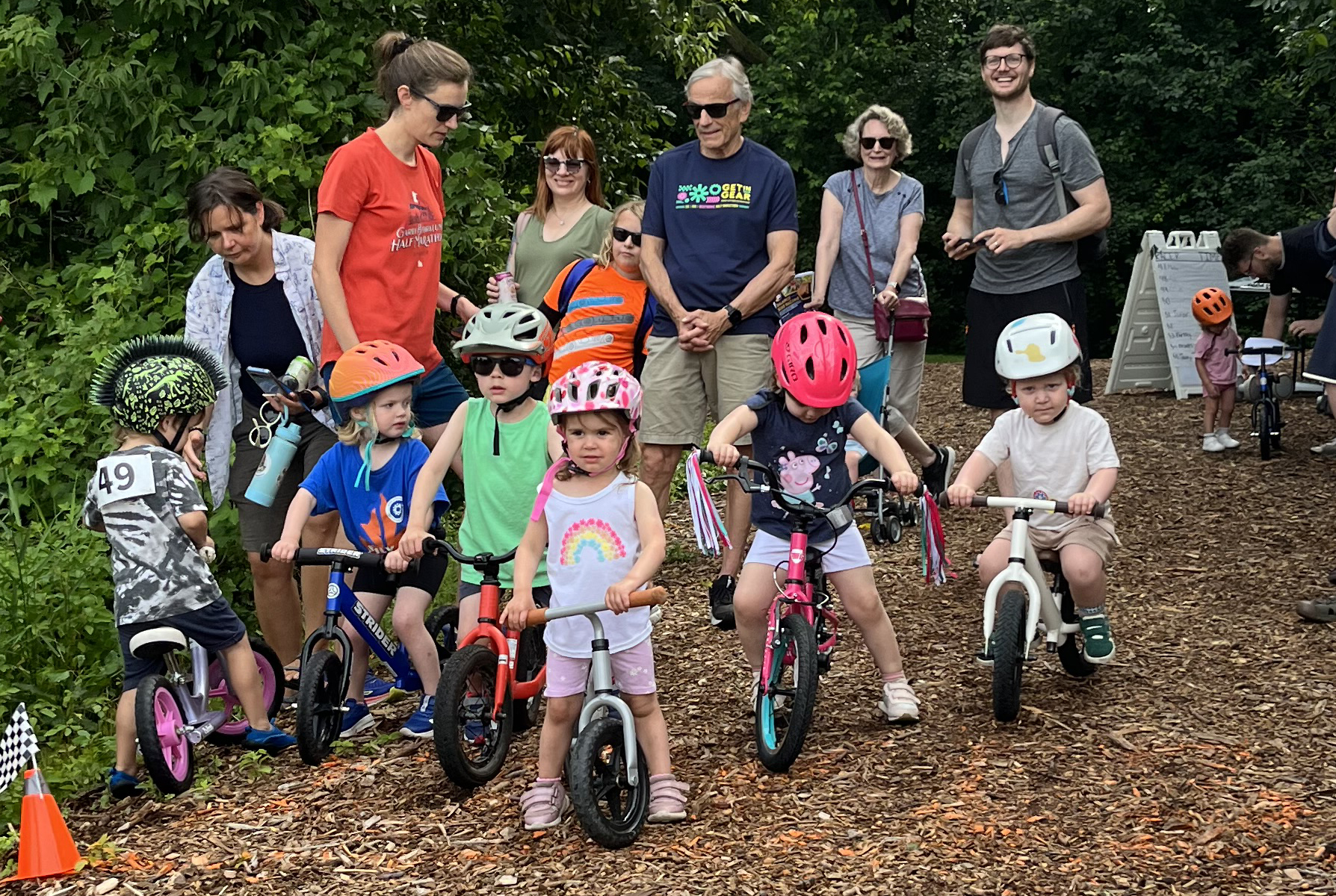 Kids lined up on balance bikes on a wood chip trail waiting to start a race