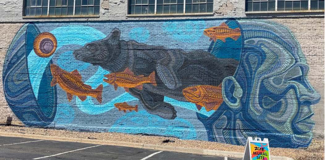 Mural by Taylor Berman, brick wall with profile of head with a bear and orange fish swimming out the back