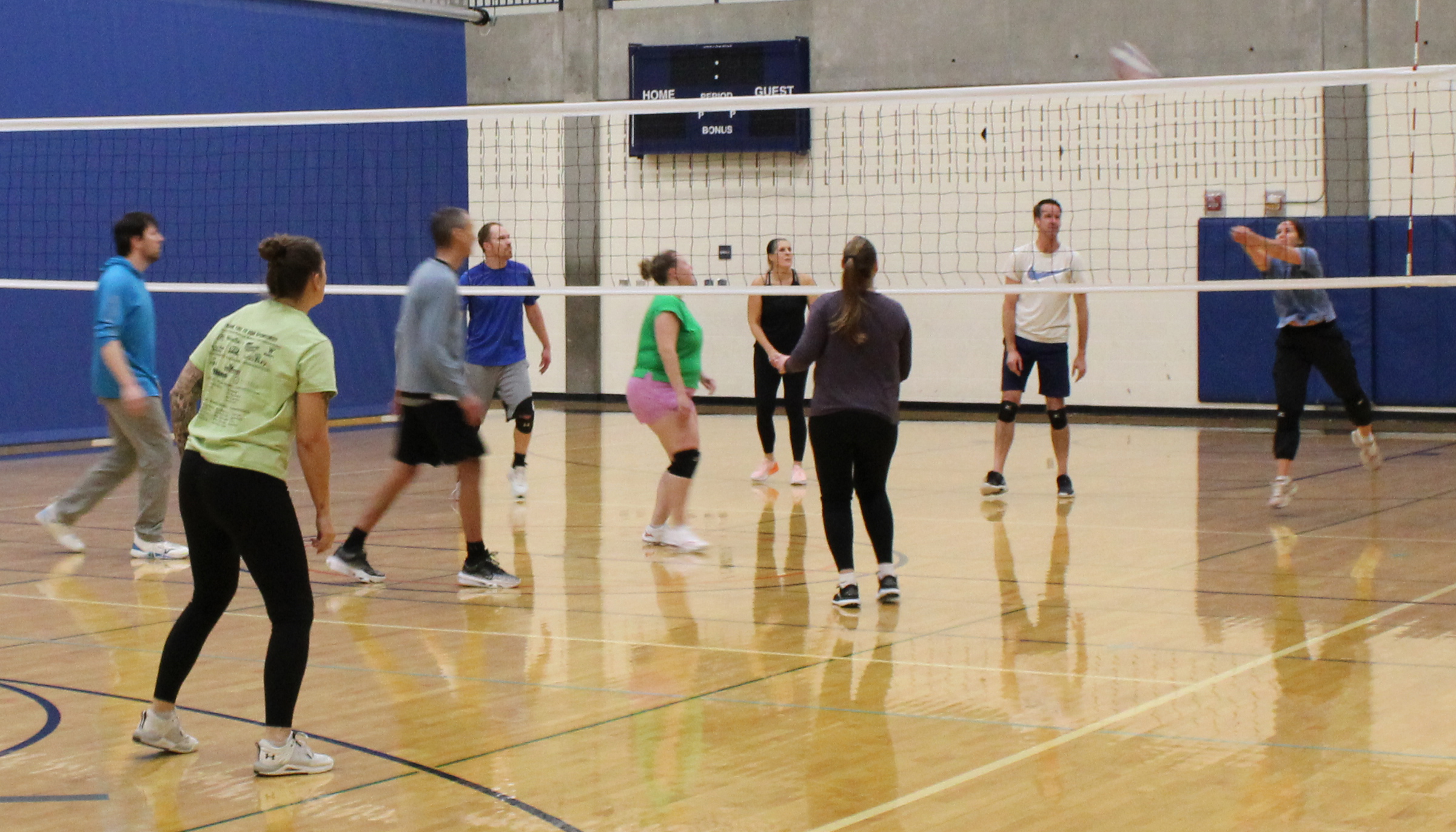 Men and women playing volleyball in a gym