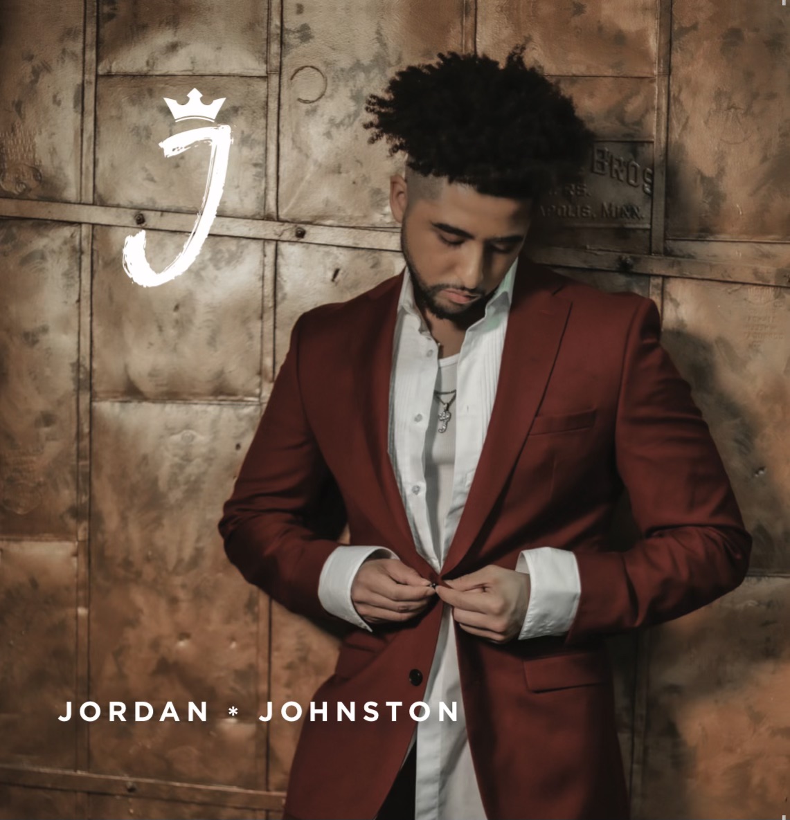 Professional photo of musical artist Jordan Johnston in a suit with his name below and letter J plus crown logo to the left