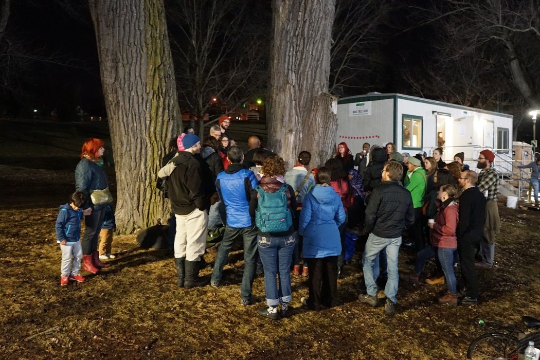 People dressed for a chilly evening, in a large group outdoors.