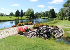 Dwan Golf Course pond with fountain and cobblestone bridge with flowers at Hole 17