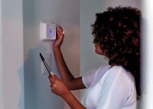 Woman adjusting thermostat in her home