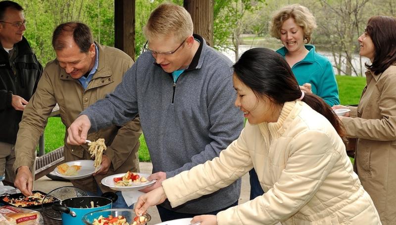 Neighbors under a park pavilion having a potluck