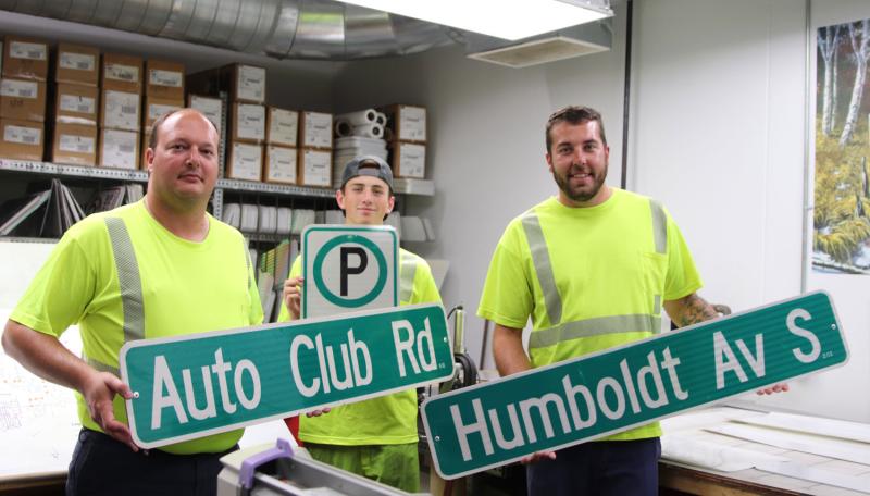 Staff holding traffic signs they've made. 