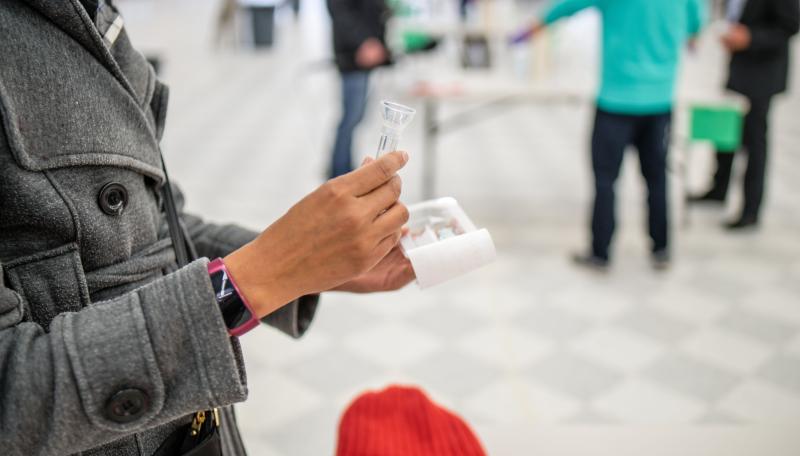 Image of woman holding a saliva test tube