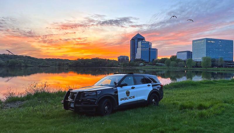 BPD squad car on a grass field, a sunset in the background.
