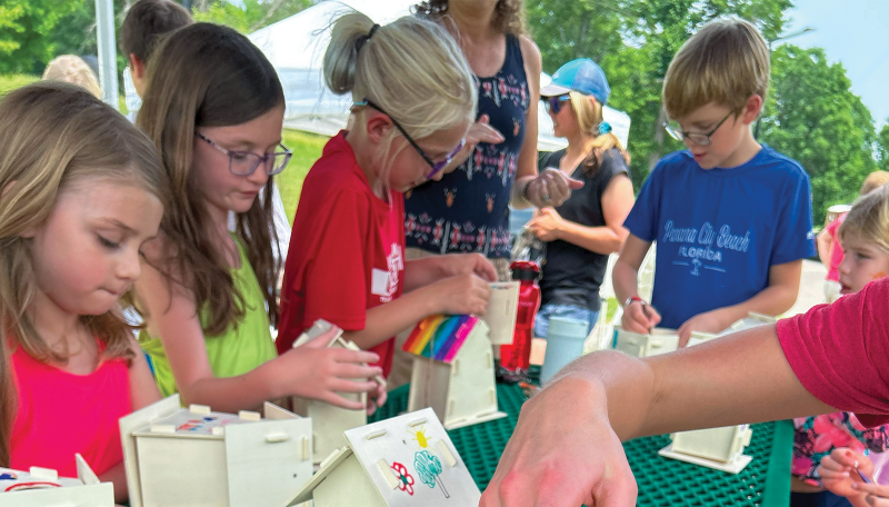 Kids making birdhouses on a picnic table during Summer Adventure Playgrounds