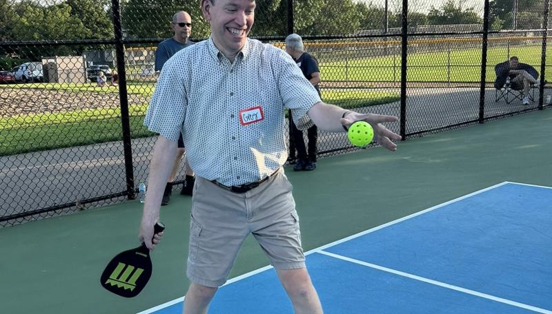Adult with disability playing pickleball outdoors on a blue court