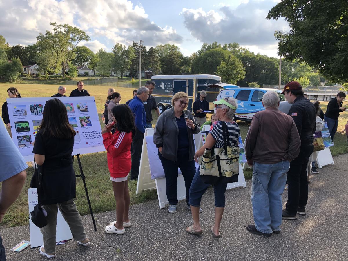 A group of adults and children attend an outdoor engagement session at Bryant Lake Park.