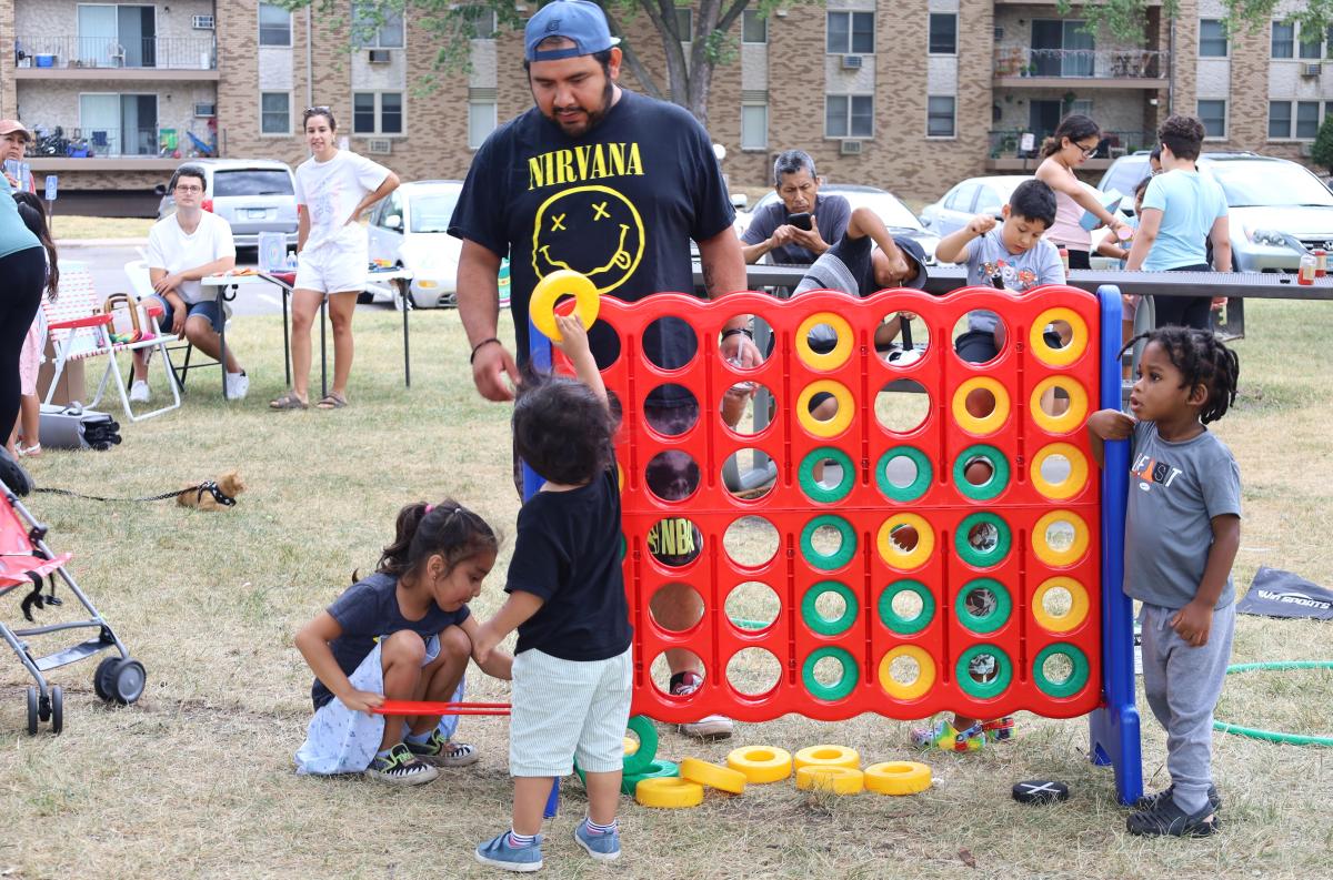 A man plays a large yard game with a group of children.