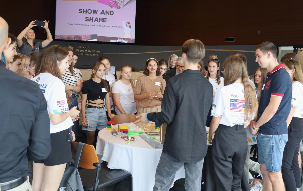 A group of visiting Ukrainian high school students gather around a table for a "show and share."
