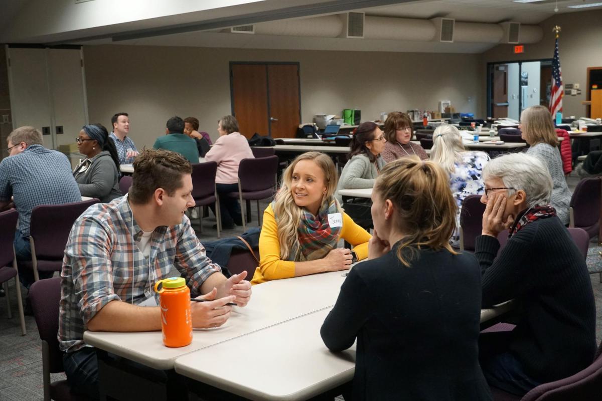 A group of participants sit around tables