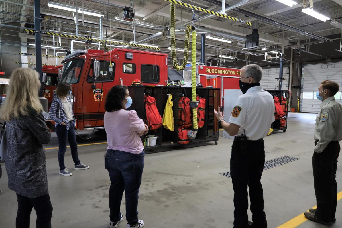 A group of participants look at a fire truck inside a fire station garage