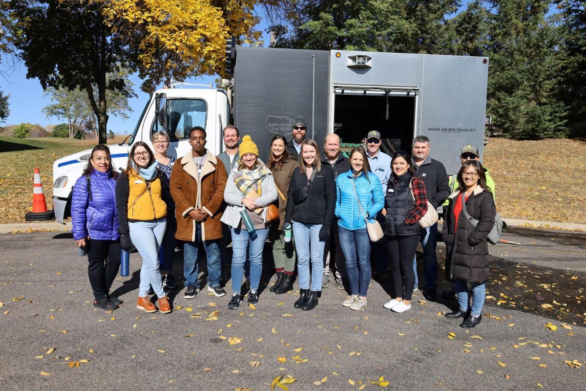 A group of participants stands outside, smiling at the camera