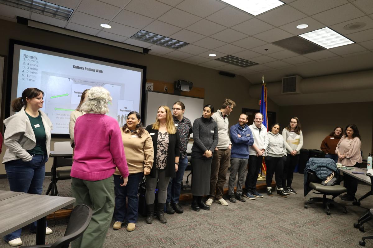 A group of individuals stand in a line in the front a conference room