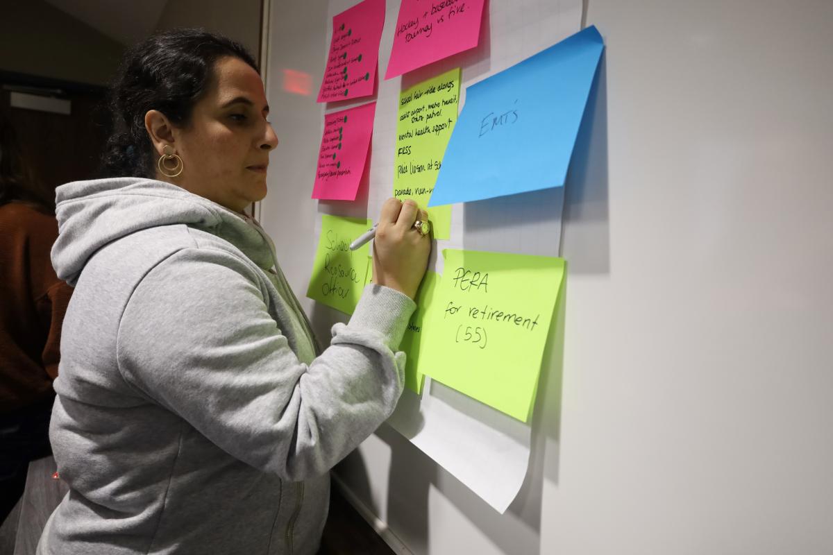 A person writes on large sticky notes on the wall