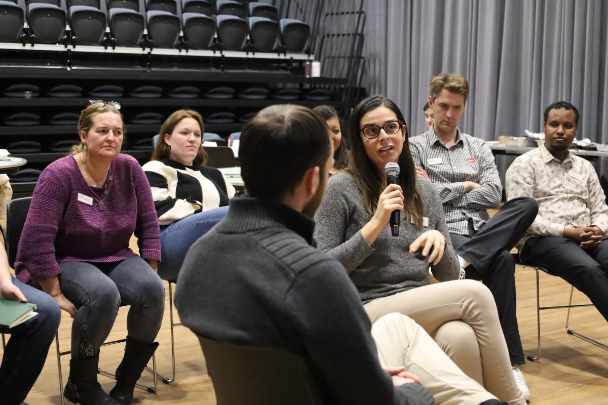 A group of people sit around someone speaking into a microphone