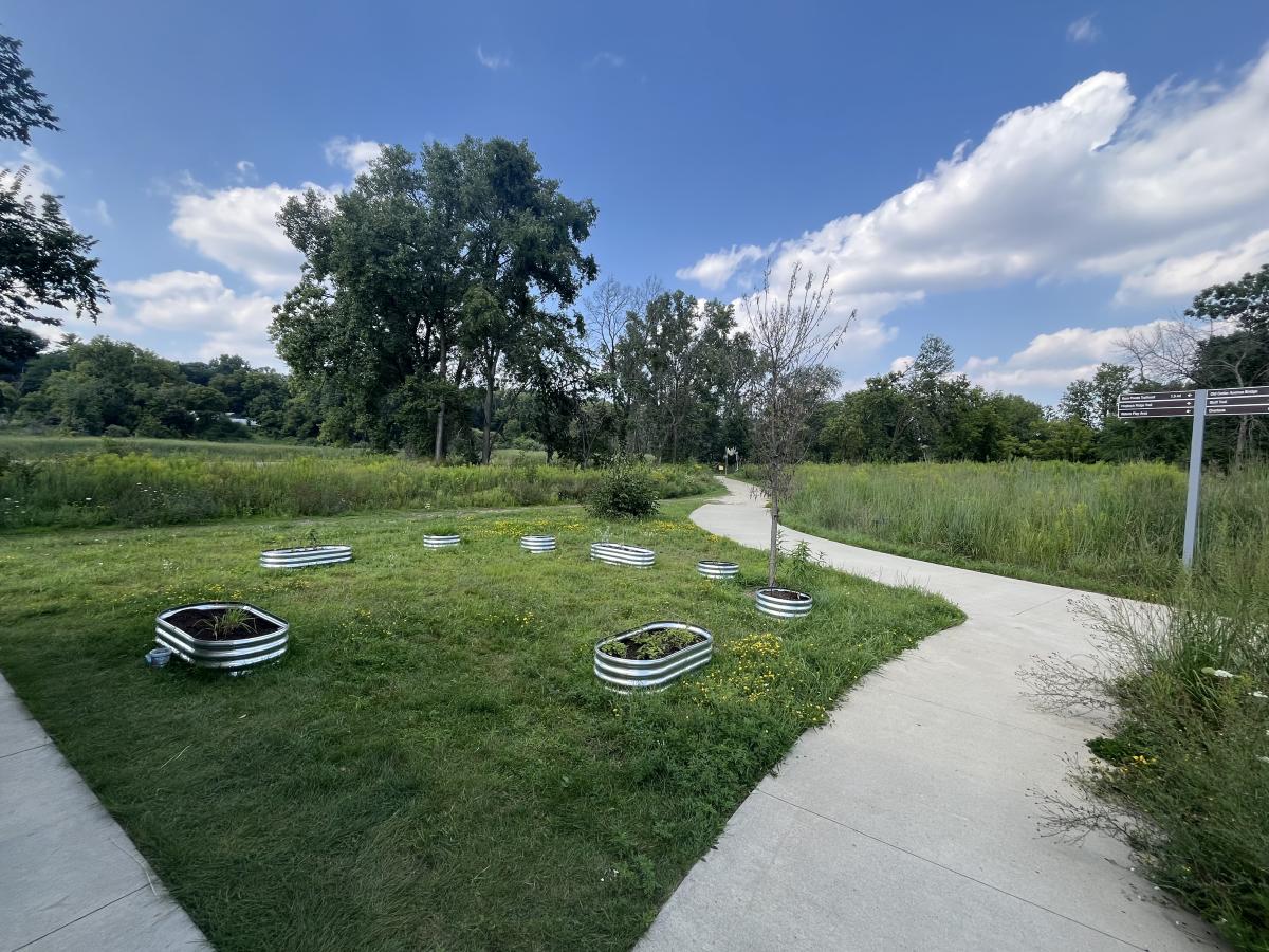 Container garden plots on grass with blue sky and surrounded by sidewalks