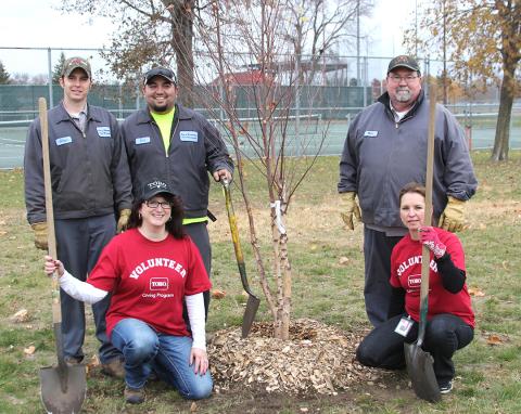 Volunteers planting trees with City staff in a park