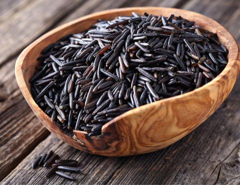 Wooden bowl with black colored wild rice on a rustic table