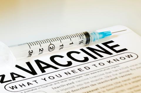Image of a syringe on top of a factsheet about vaccines