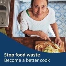 Woman cutting veggies in the kitchen, smiling upward