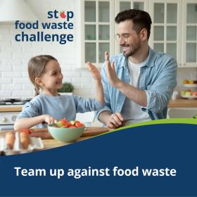 child and father high-five in the kitchen. banner with text says "team up against food waste."
