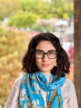 Woman with dark hair and glasses with blue floral scarf